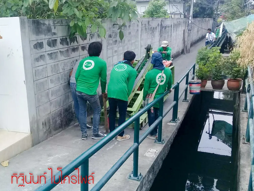 ทีมงานเข็นปั้นจั่นไปตามทางแคบข้างกำแพงและร่องน้ำ