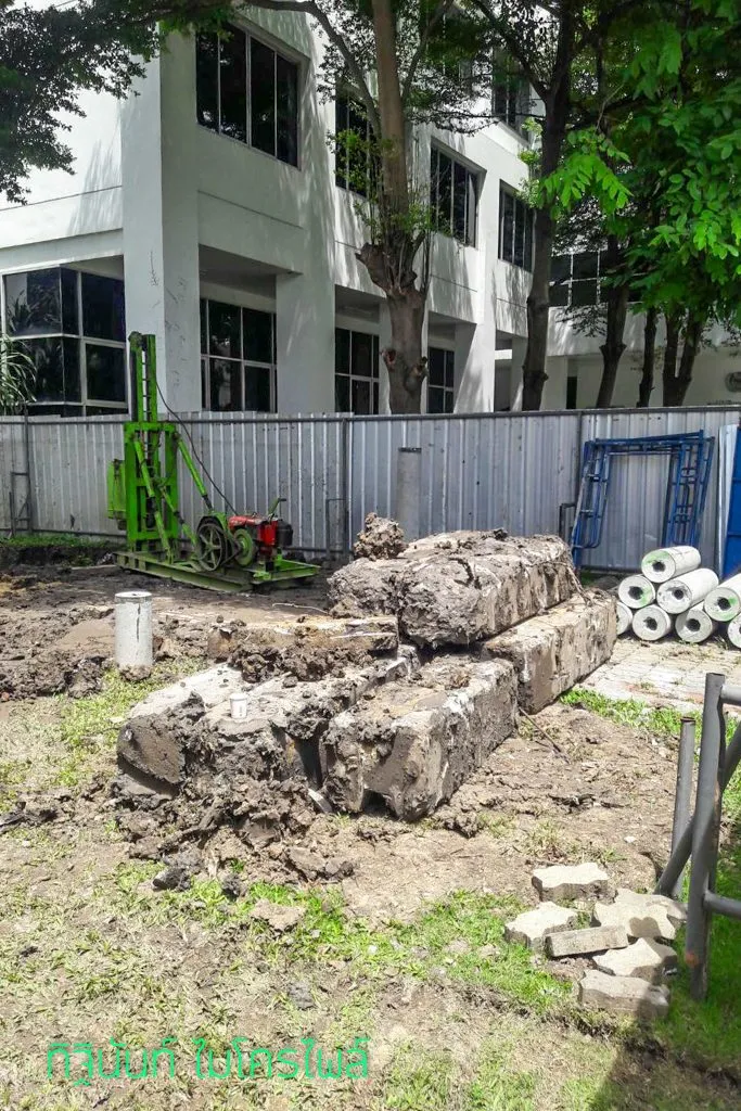 ภาพรวมพื้นที่ก่อสร้างที่มีปั้นจั่น ท่อนเสาเข็ม และวัสดุรื้อถอน