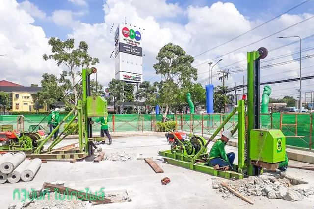 ปั้นจั่นไมโครไพล์สองชุดทำงานบนลานคอนกรีตหน้าป้าย AEC Trade Center