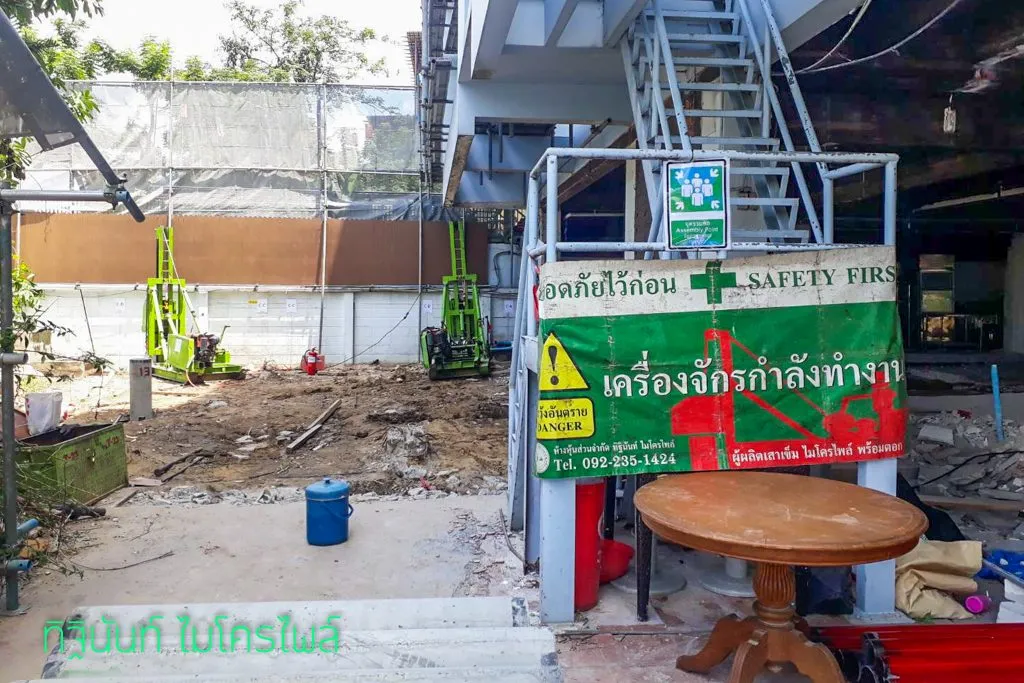 ป้ายเตือนเครื่องจักรกำลังทำงานและปั้นจั่นสองชุดภายในพื้นที่ก่อสร้าง